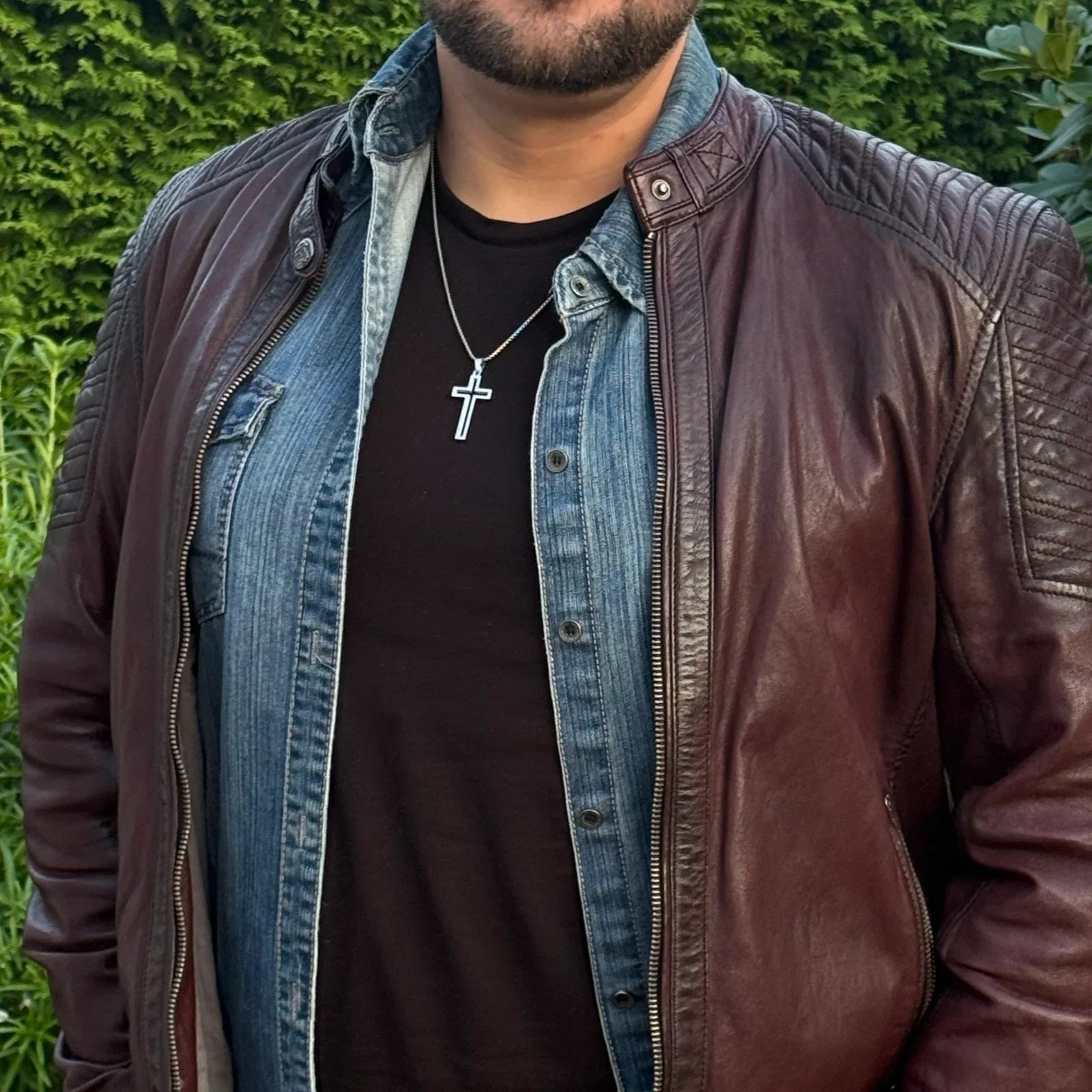 Männer-Halskette mit Kreuz-Anhänger aus Edelstahl, getragen über Jeanshemd und Lederjacke
