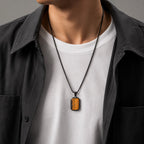 Männer-Halskette mit rechteckigem Tigerauge-Anhänger, schwarzem Edelstahlkettchen, stilvoll kombiniert mit weißem T-Shirt und dunkler Jacke